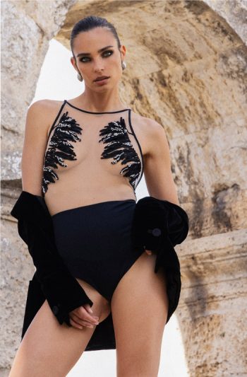 Nadia One-Piece 22 Moorea Swim Nadia one piece in black sheer illusion tulle bodice with hand embroidered chiffon petals and glass beads poised under ancient stone arch